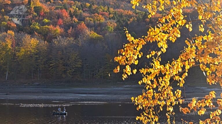 Fishermen crappie fishing in the fall on a serene lake or river during fall, with colorful leaves reflecting on the water's surface.